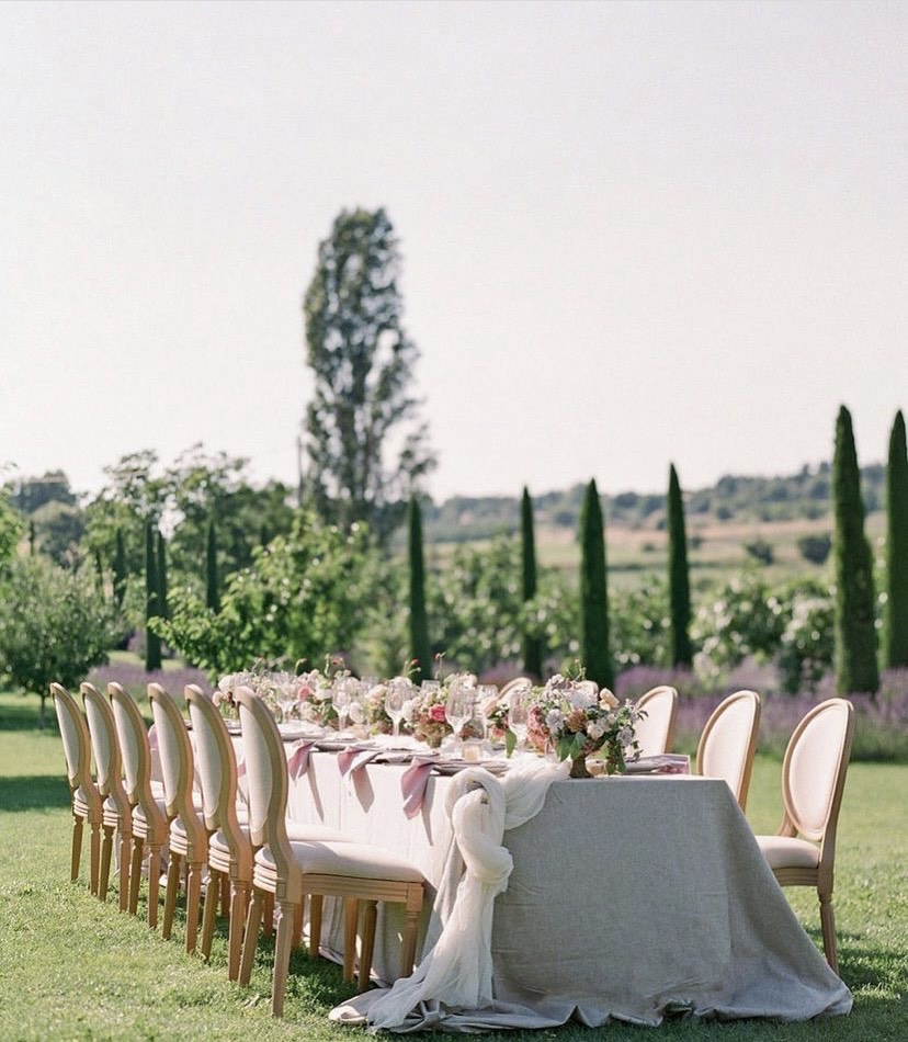 A romantic outdoor reception table set up amidst lush greenery and cypress trees at Abbaye Saint-Eusèbe, perfect for a Provence France wedding with timeless countryside charm.