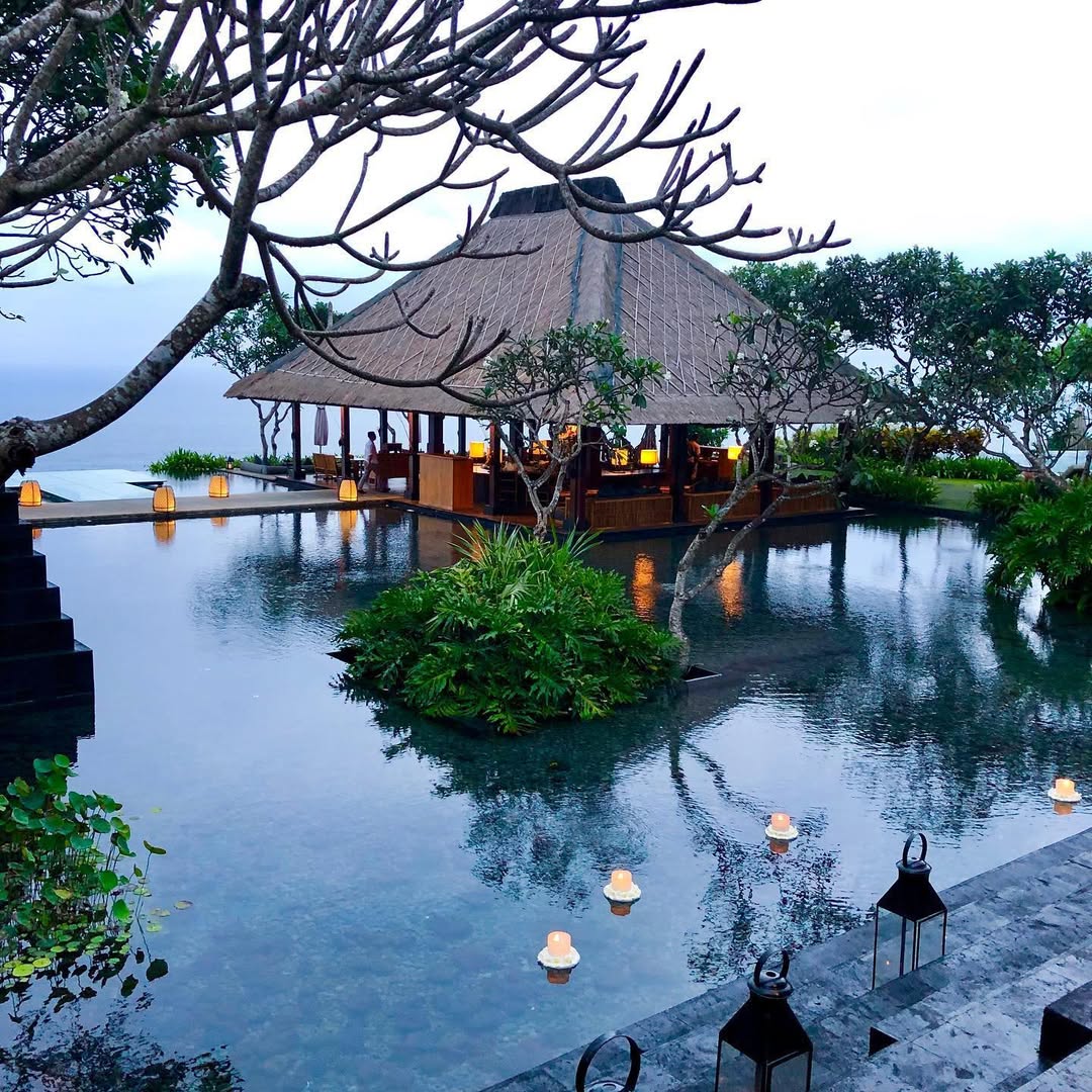 Romantic Bali island wedding venue with thatched roof pavilion surrounded by tranquil water at Bvlgari Resort.