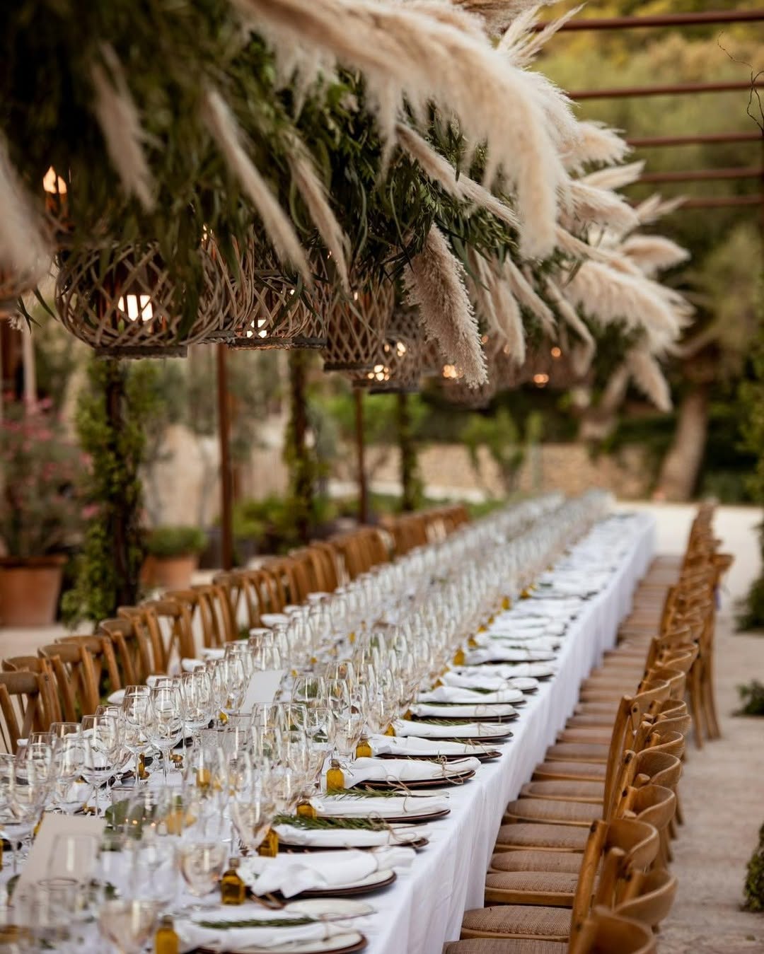 Rustic long table outdoor wedding dinner decorated with pampas grass and greenery at Castell Son Claret Mallorca.