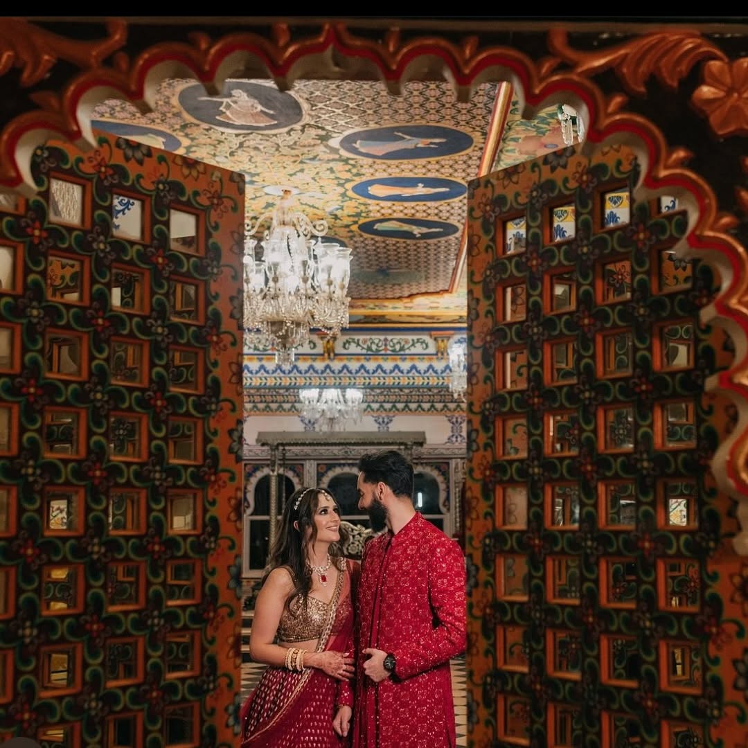 Bride and groom in traditional Indian attire during their Udaipur wedding at Chunda Palace, featuring intricate royal Rajasthani architecture.