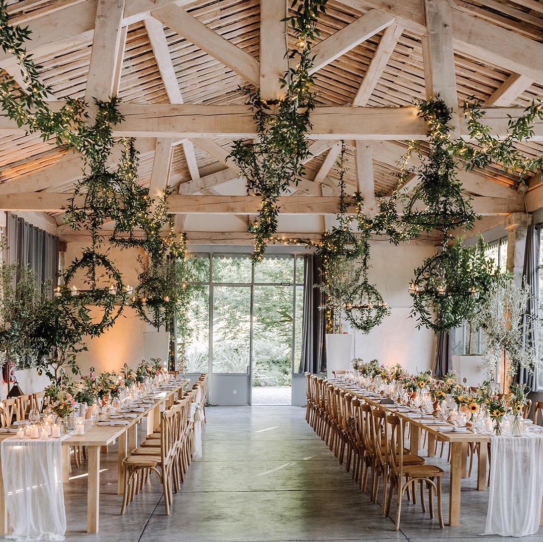 Indoor wedding reception at Domaine de Blanche Fleur adorned with suspended greenery and twinkling lights, capturing the enchanting ambiance of a Provence France wedding.