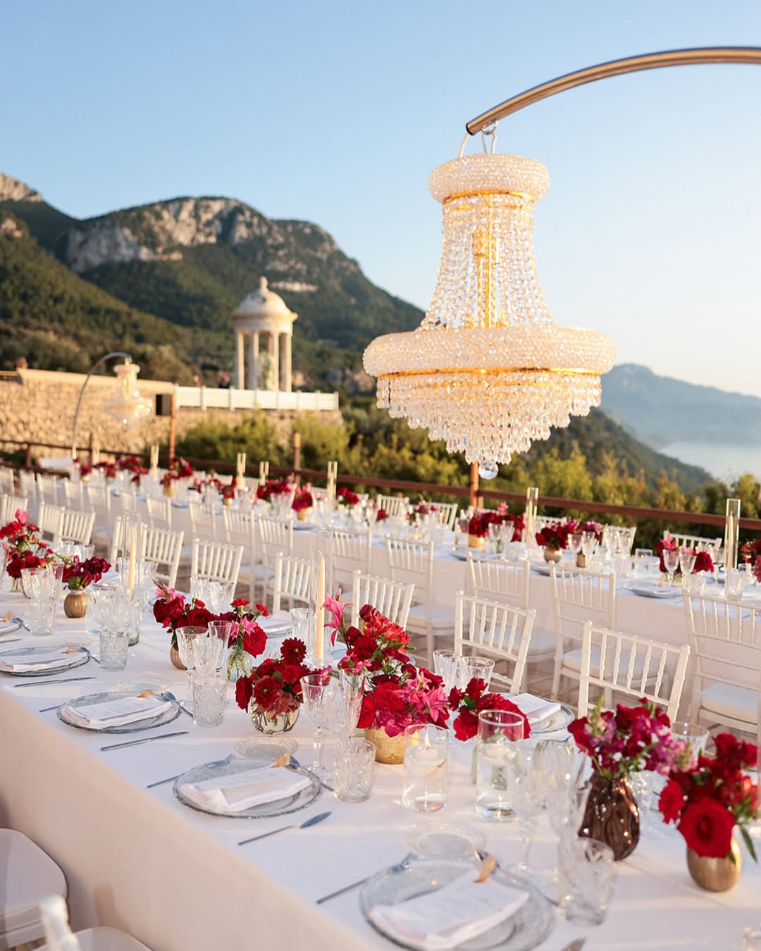 Glamorous outdoor wedding reception with red florals and crystal chandeliers at Son Marroig Mallorca.