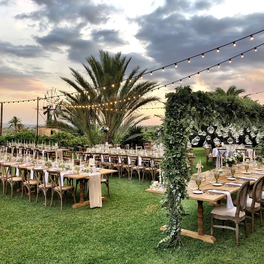 Whimsical garden wedding reception with greenery-hung decor and sunset views at Son Mir Mallorca.