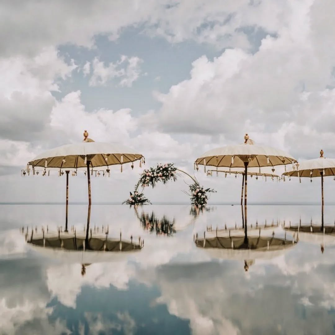 Scenic sky wedding altar with Balinese umbrellas and ocean backdrop at The Edge Bali island wedding venue.