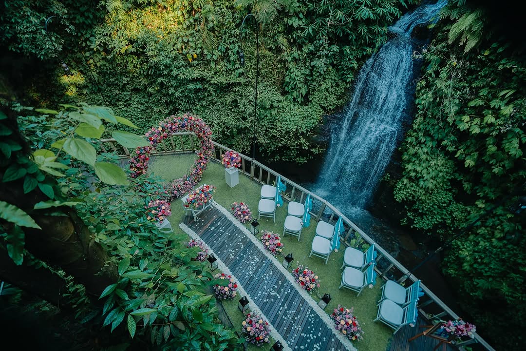 Waterfall-side Bali island wedding ceremony at The Kayon Resort with lush greenery and romantic floral arch.