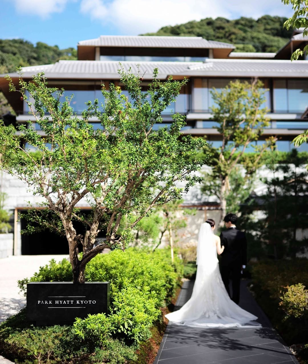 Bride and groom walking in the serene courtyard of Park Hyatt Kyoto, surrounded by manicured greenery and modern Japanese architecture—an ideal Kyoto wedding venue blending luxury and tradition.